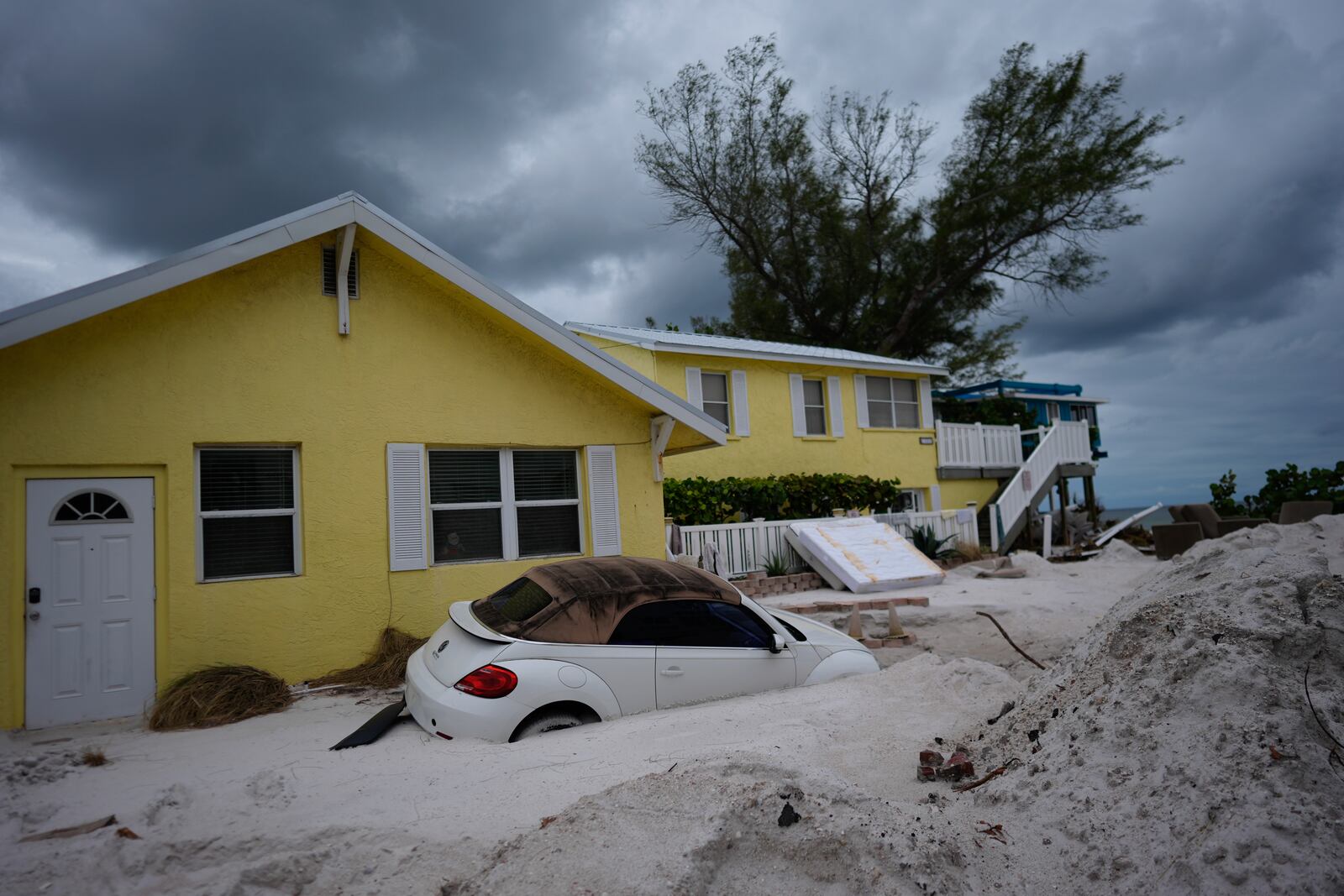 A car sits half-buried in sand as Bradenton Beach, Fla., which was in the process of cleaning up after Hurricane Helene, as Hurricane Milton approaches on Anna Maria Island, Tuesday, Oct. 8, 2024. (AP Photo/Rebecca Blackwell)