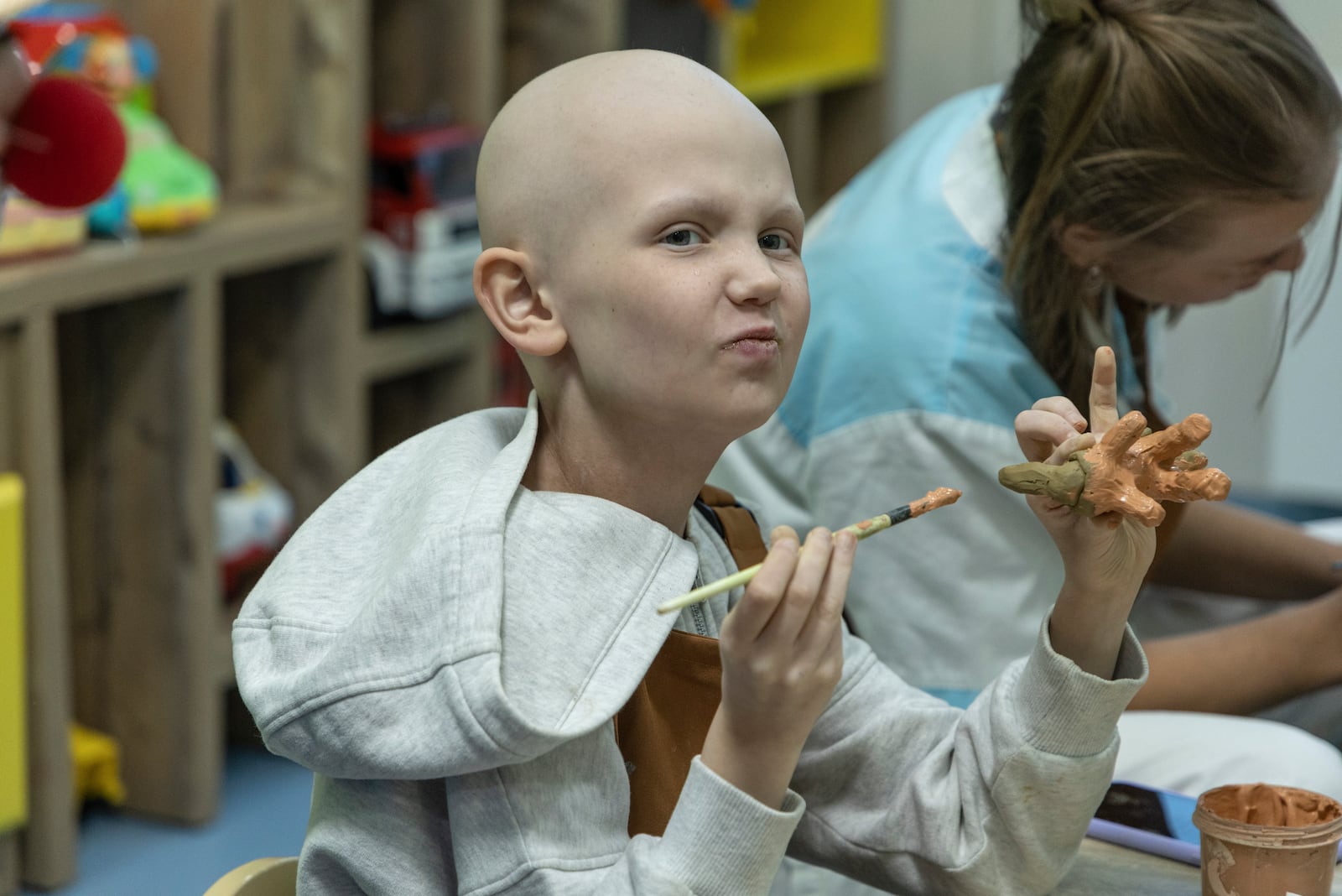 Kira Vertetska, 8, who is undergoing treatment in the oncology department at Okhmatdyt children's hospital in Kyiv, Ukraine, paints a clay figure Thursday Sept. 19, 2024. (AP Photo/Anton Shtuka)