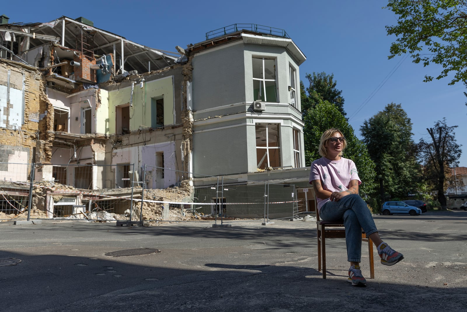 Olha Bulkina, 35, co-founder of the "Bureau of Smiles and Support" sits in front of Okhmatdyt children's hospital in Kyiv, Ukraine Saturday Sept. 14, 2024 which was destroyed after a Russian missile strike on July 8. (AP Photo/Anton Shtuka)