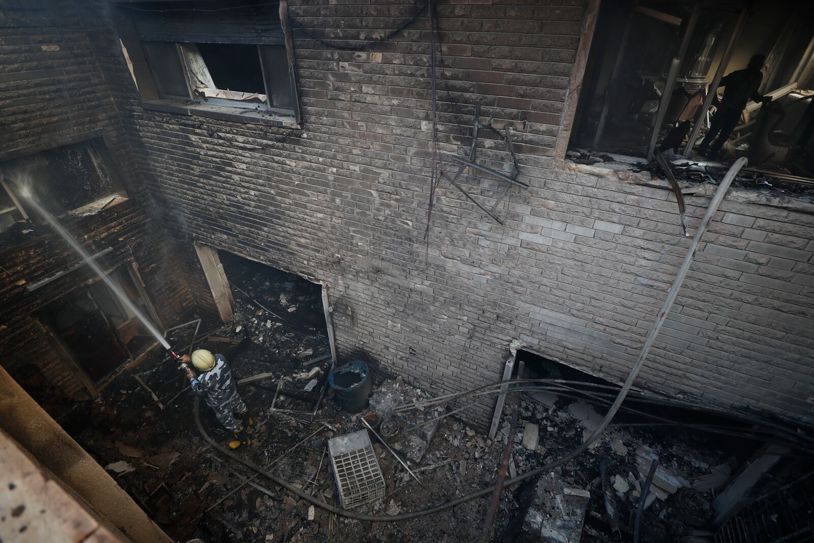 A firefighter hoses down a building hit in an Israeli airstrike in Damascus, Syria, Thursday, Nov. 14, 2024. (AP Photo/Omar Sanadiki)