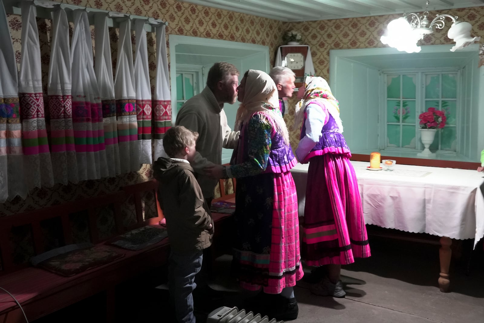 Yuri Strukov, second left, his son Ilya, left, and his daughters Daria and Nina in traditional Doukhobor dresses embrace each other after Easter prayer at the former Orphanage house where Doukhobors has worshiped for years, in the remote mountain village of Gorelovka, Georgia, Saturday, May 4, 2024. (AP Photo/Kostya Manenkov)