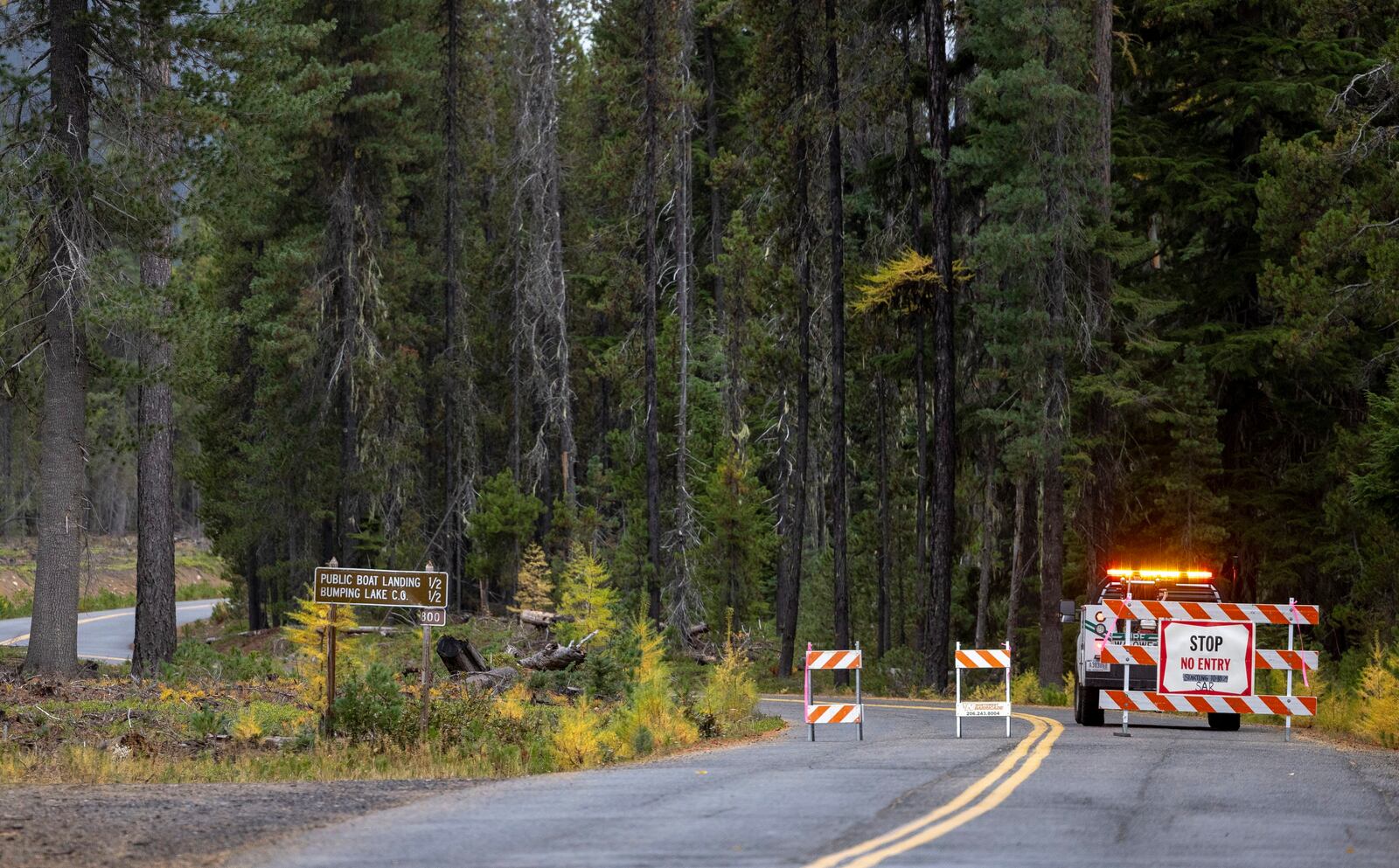 A U.S. Forest Service worker sits at a roadblock leading to the Twin Sisters Lakes trailhead as the search for two Navy aviators continues on Friday, Oct. 18, 2024, near Goose Prairie, Yakima County, Wash. (Nick Wagner/The Seattle Times via AP)