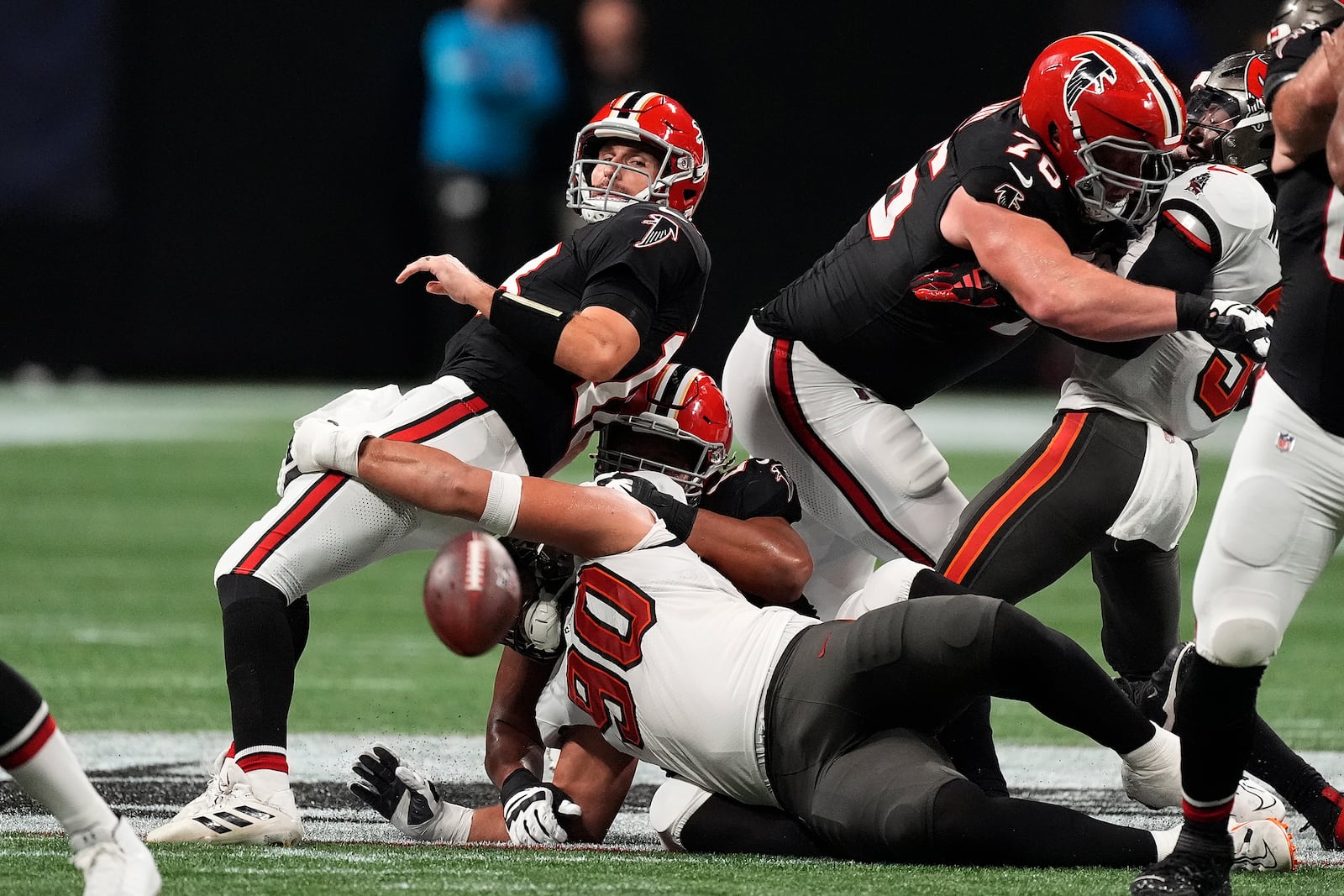 Atlanta Falcons quarterback Kirk Cousins (18) loses the football as he is sacked by Tampa Bay Buccaneers defensive end Logan Hall (90) during the first half of an NFL football game Thursday, Oct. 3, 2024, in Atlanta. (AP Photo/John Bazemore)