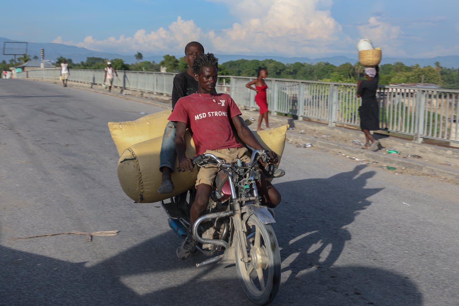 People cross a bridge in Pont-Sonde, Haiti, Tuesday, Oct. 8, 2024, days after a deadly gang attack in the town. (AP Photo/Odelyn Joseph)