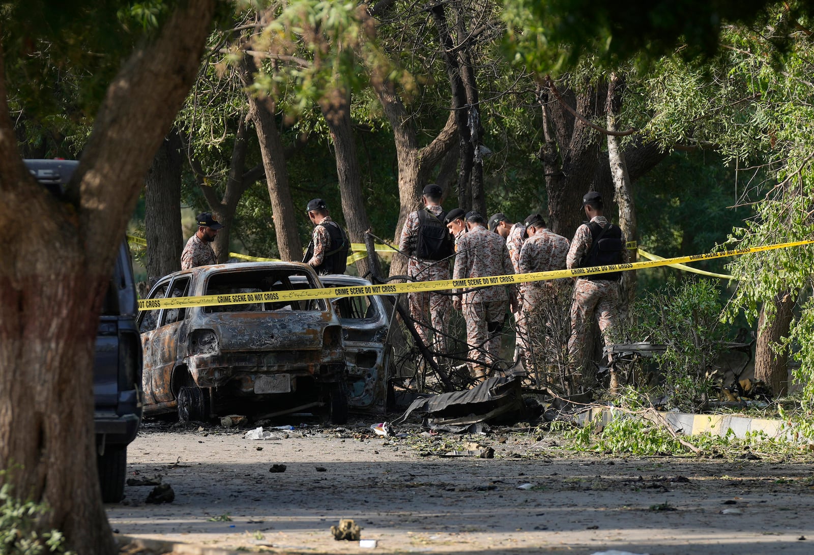 Security officials work on the site of an explosion that caused injures and destroyed vehicles outside the Karachi airport, Pakistan, Monday, Oct. 7, 2024. Pakistani Baloch separatists claim deadly bomb attack that killed 2 Chinese near Karachi airport. (AP Photo/Fareed Khan)