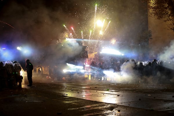 Demonstrators use petard against police as police blocked a street to prevent protesters rallying against the governments' decision to suspend negotiations on joining the European Union for four years, outside the parliament's building in Tbilisi, Georgia, early Saturday, Nov. 30, 2024. (AP Photo/Zurab Tsertsvadze)