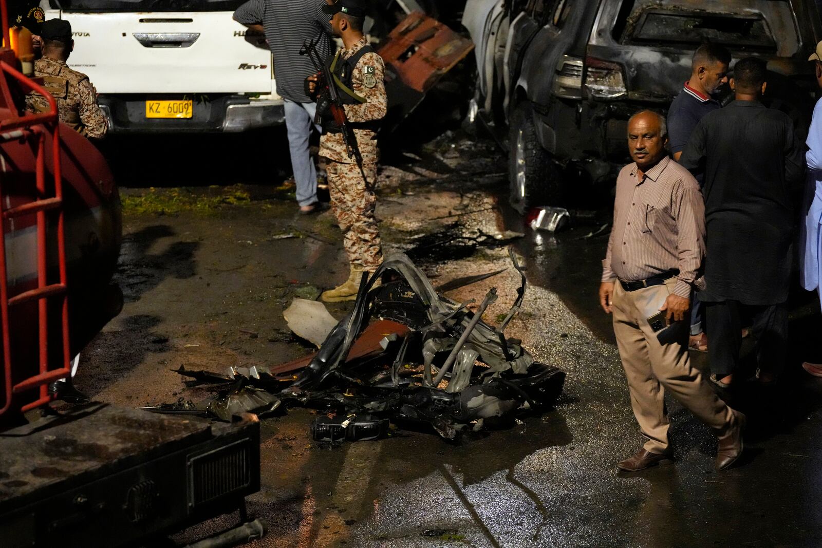 Security officials examine the site of an explosion that caused injures and destroyed vehicles outside the Karachi airport, Pakistan, early Monday, Oct. 7, 2024. (AP Photo/Fareed Khan)