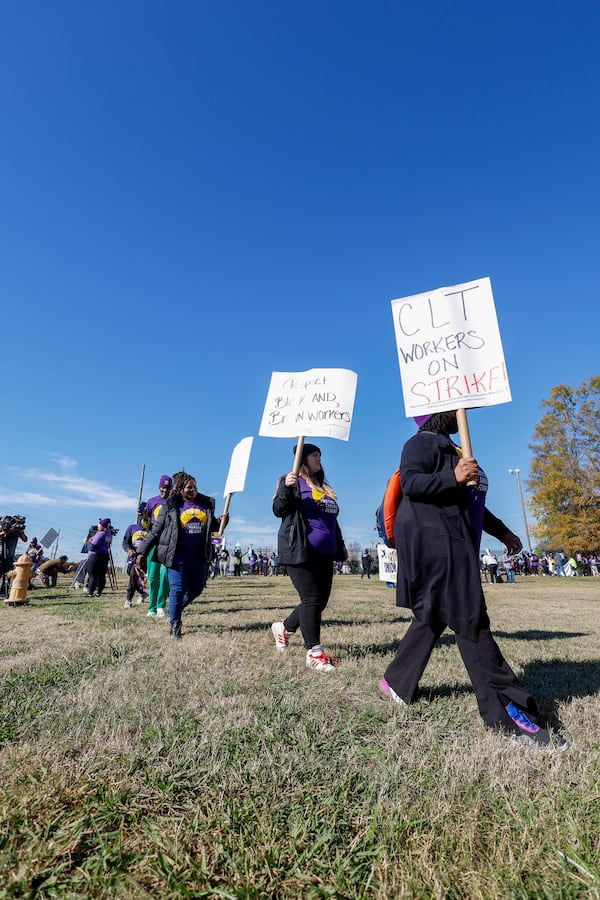 Airport workers wave signs as they march in front of the Charlotte Douglas International Airport in Charlotte, N.C., Monday, Nov. 25, 2024. (AP Photo/Nell Redmond)