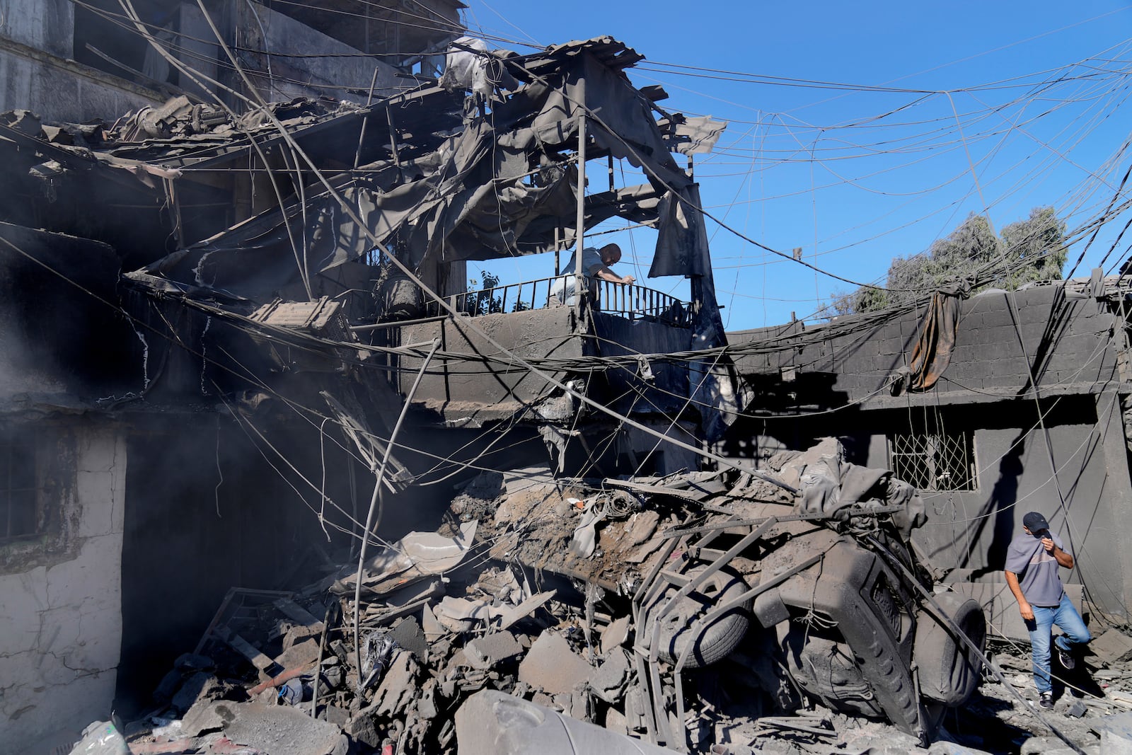 A man, top, checks his destroyed house at a popular neighbourhood that was hit Monday night by Israeli airstrikes, south of Beirut, Lebanon, Tuesday, Oct. 22, 2024. (AP Photo/Hussein Malla)