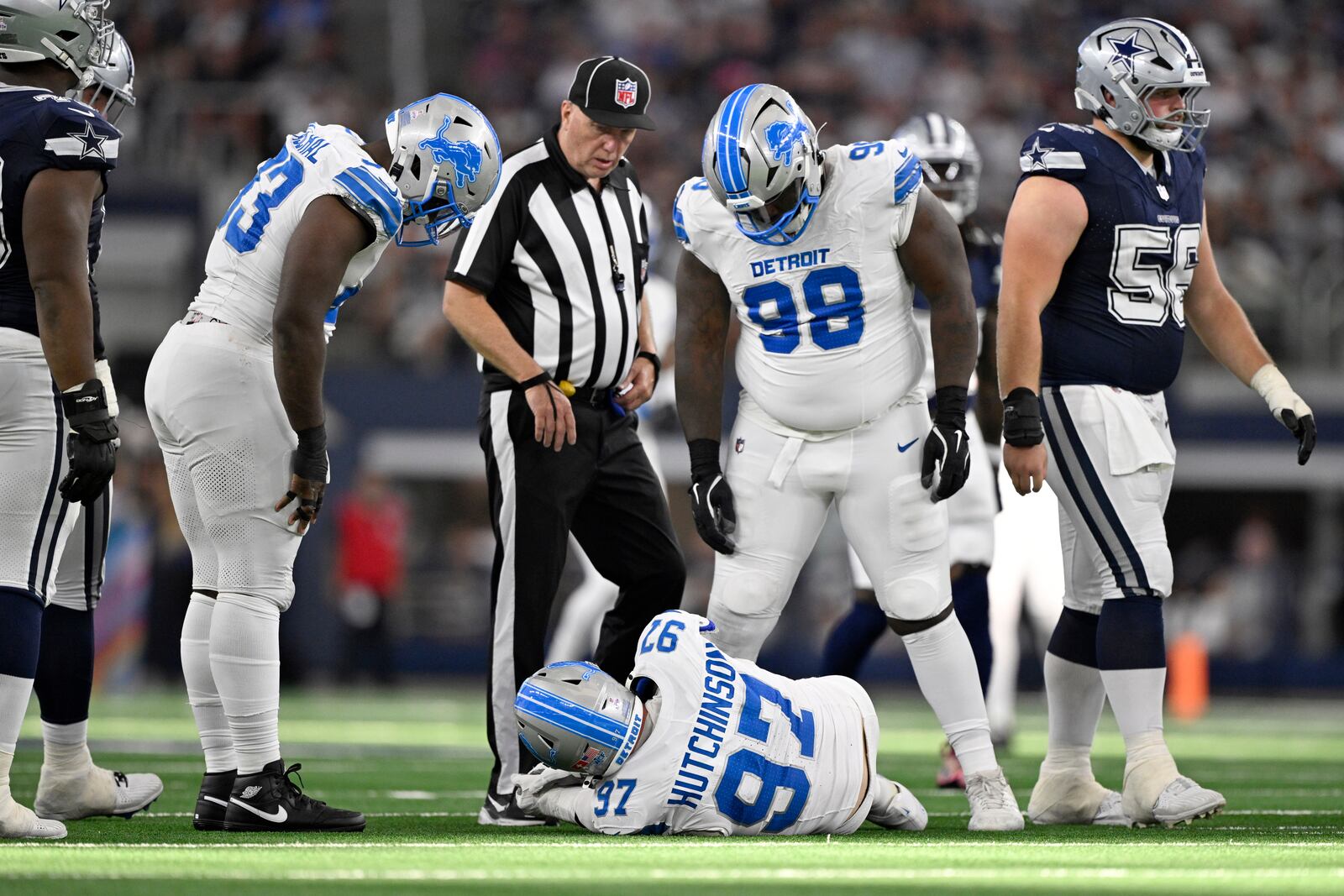 Detroit Lions' Aidan Hutchinson (97) is checked on by DJ Reader (98) and others after suffering an unknown injury in the second half of an NFL football game against the Dallas Cowboys in Arlington, Texas, Sunday, Oct. 13, 2024. (AP Photo/Jerome Miron)