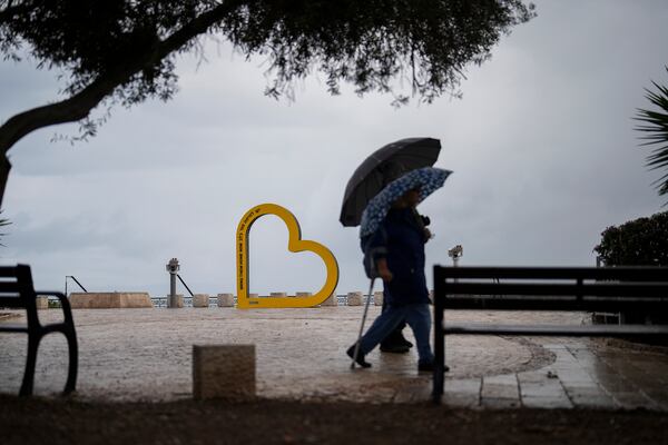 People walk past a sign reading in Hebrew and English "Bring them home now" in reference of the of hostages held in the Gaza Strip by the Hamas militant group, in Haifa, Israel, Tuesday, Nov. 26, 2024. (AP Photo/Francisco Seco)