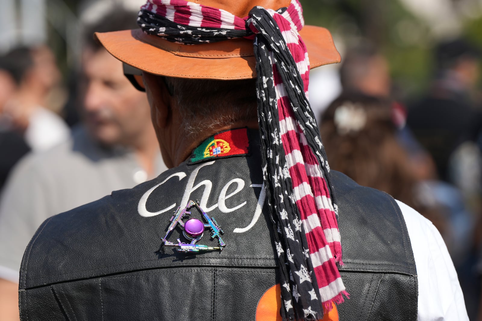 A man wearing a pin with rifles on his vest and the Stars and Stripes on his hat walks at the Roman Catholic holy shrine of Fatima during the IX Pilgrimage of the Blessing of Helmets that draws tens of thousands, in Fatima, Portugal, Sunday, Sept. 22, 2024. (AP Photo/Ana Brigida)