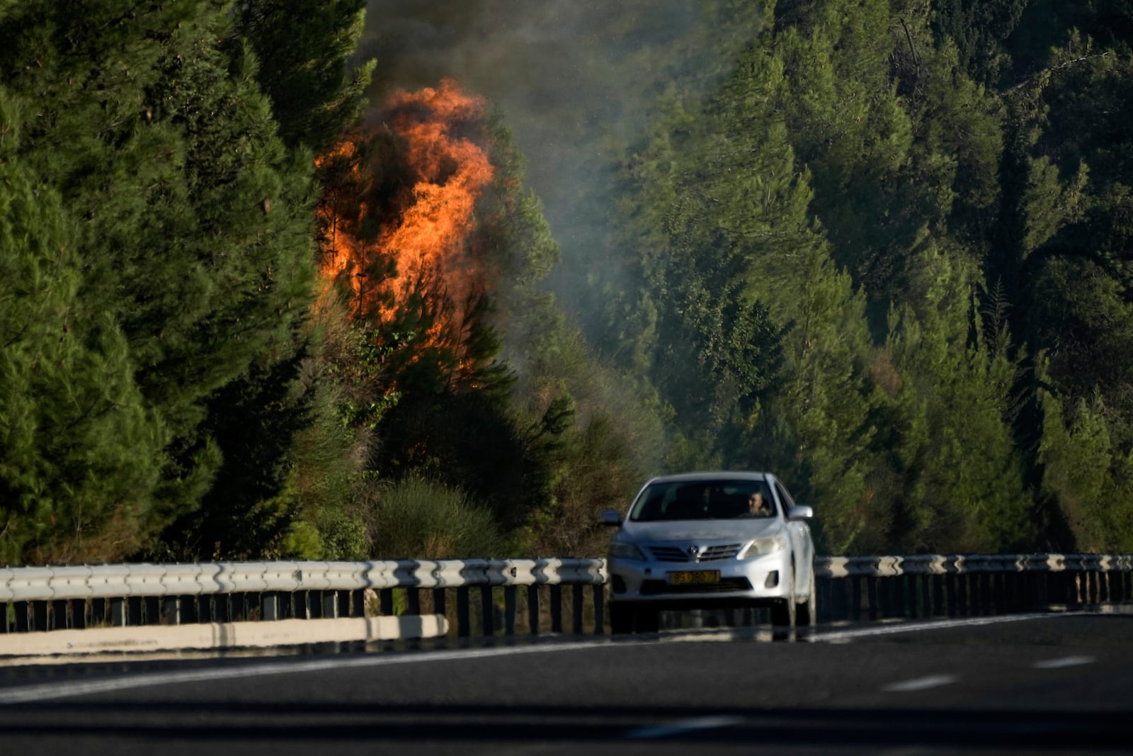 A car passes next to a fire after a rocket fired from Lebanon hit northern Israel on Saturday, Sept. 21, 2024. (AP Photo/Leo Correa)