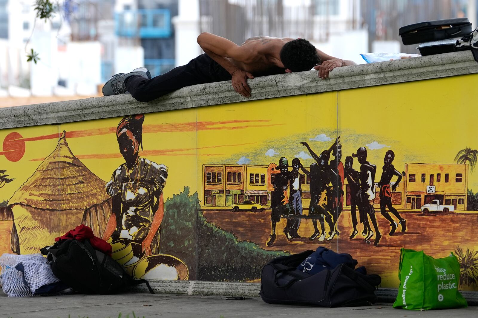 A homeless man who goes by the name of CJ lies on top of a brick wall on the first day of a statute that took effect, making it illegal in Florida to sleep on sidewalks, in parks, on beaches or in other public spaces — one of the country's strictest anti-homelessness laws, Tuesday, Oct. 1, 2024, in Fort Lauderdale, Fla. (AP Photo/Lynne Sladky)