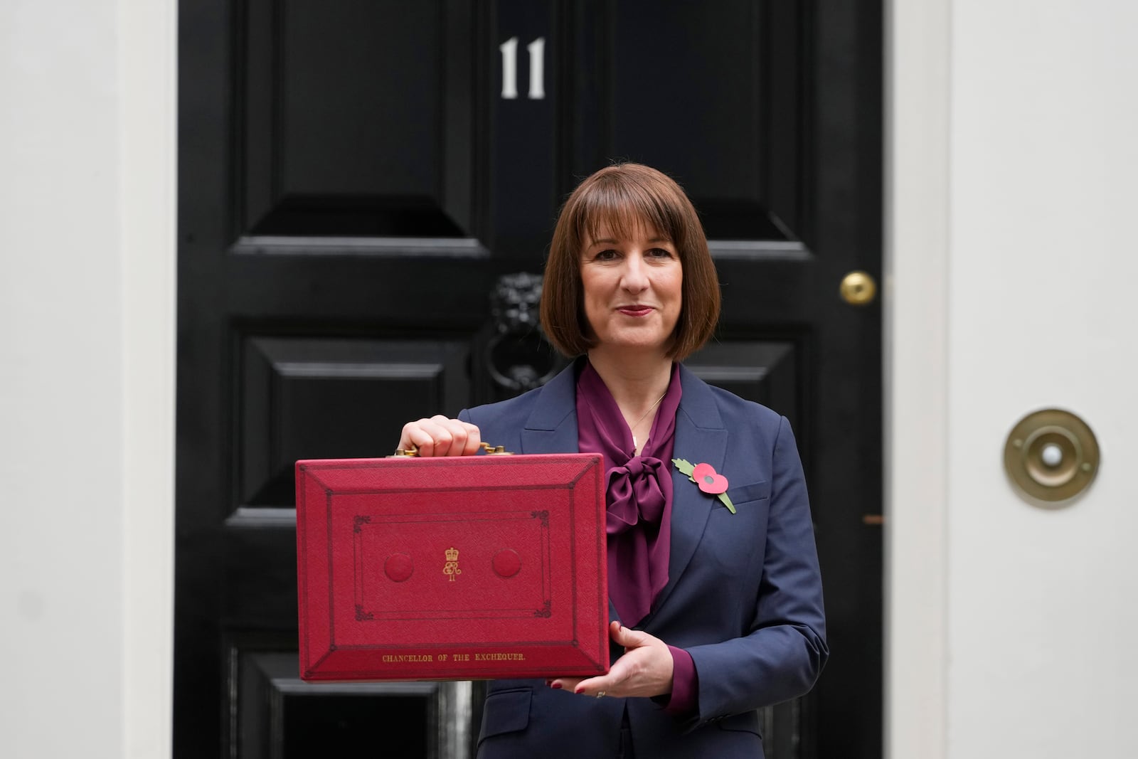 Britain's Chancellor of the Exchequer, Rachel Reeves, holds up the traditional red ministerial box containing her budget speech, as she poses for the media outside No 11 Downing Street, before departing to the House of Commons to deliver the budget in London, Wednesday, Oct. 30, 2024. (AP Photo/Kirsty Wigglesworth)