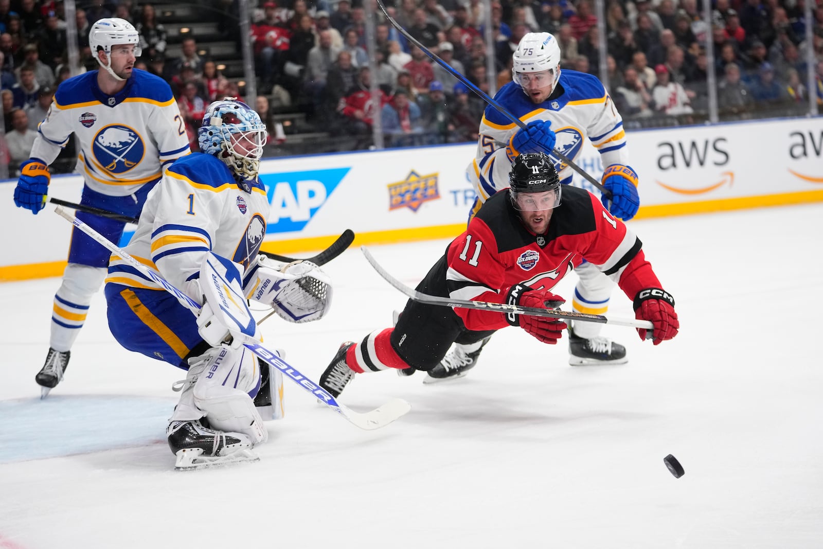 New Jersey Devils' Stefan Noesen, right, and Buffalo Sabres' goaltender Ukko-Pekka Luukkonen battle for the puck during the NHL hockey game between Buffalo Sabres and New Jersey Devils, in Prague, Czech Republic, Friday, Oct. 4, 2024. (AP Photo/Petr David Josek)