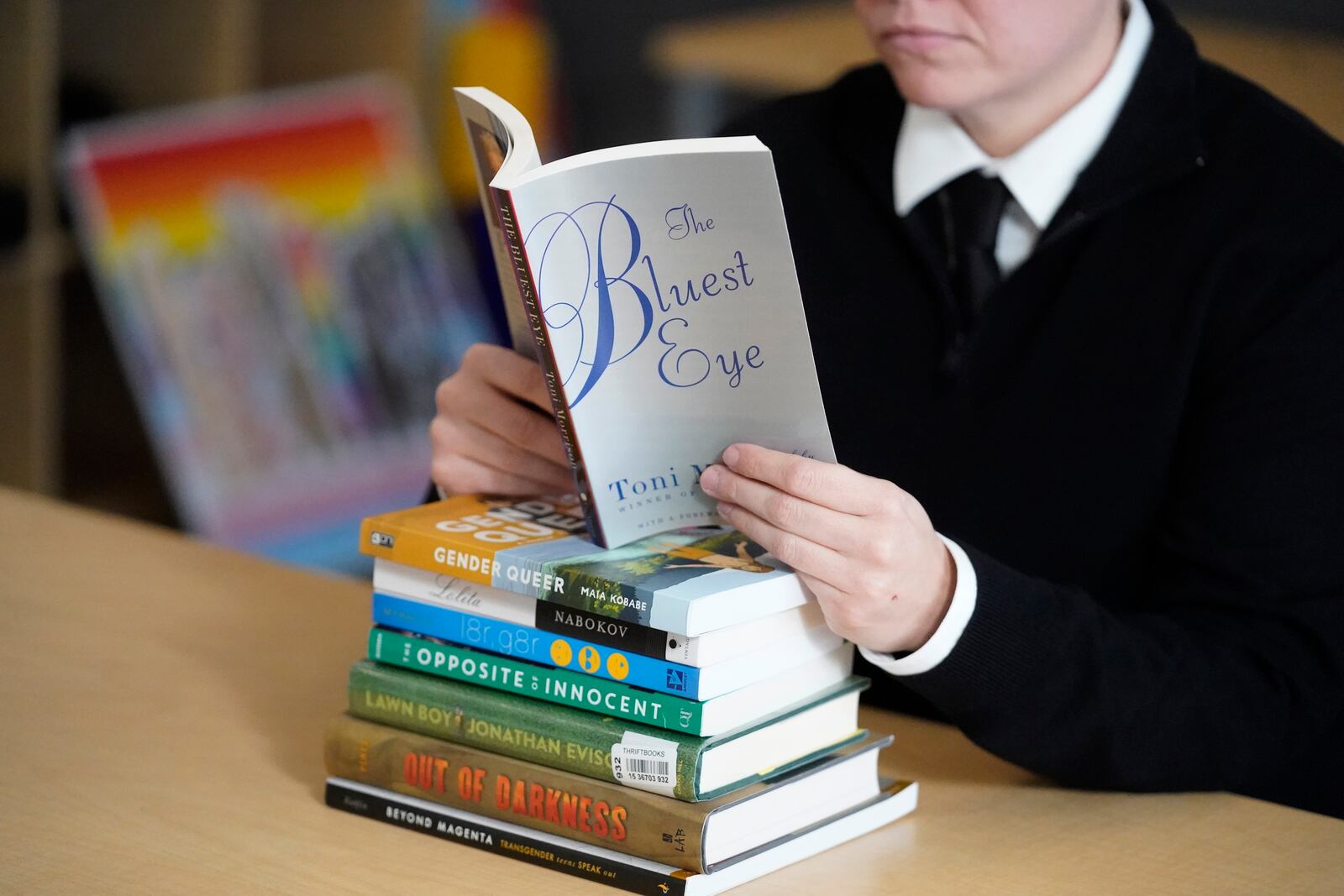 FILE - Amanda Darrow, director of youth, family and education programs at the Utah Pride Center, poses with books, including "The Bluest Eye," by Toni Morrison, that have been the subject of complaints from parents in Salt Lake City on Dec. 16, 2021. (AP Photo/Rick Bowmer, File)