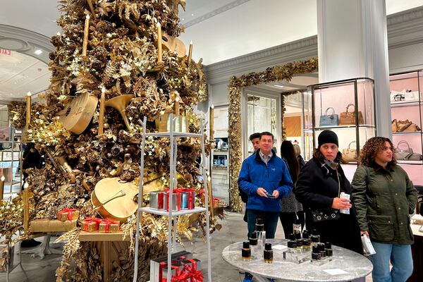 Shoppers pass a Christmas tree at the Bergdorf Goodman store on Sunday, Nov. 24, 2024, in New York. (AP Photo/Anne D'Innocenzio)