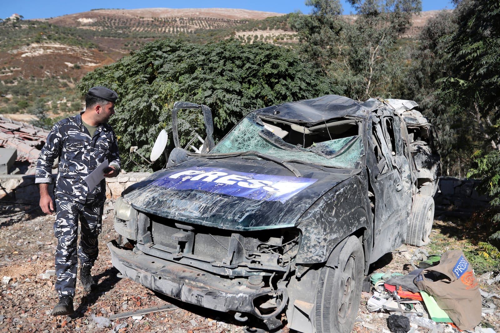 A policeman checks a destroyed journalists' car, at the site where an Israeli airstrike hit a compound housing journalists, killing three media staffers from two different news agencies according to Lebanon's state-run National News Agency, in Hasbaya village, southeast Lebanon, Friday, Oct. 25, 2024. (AP Photo/Mohammed Zaatari)