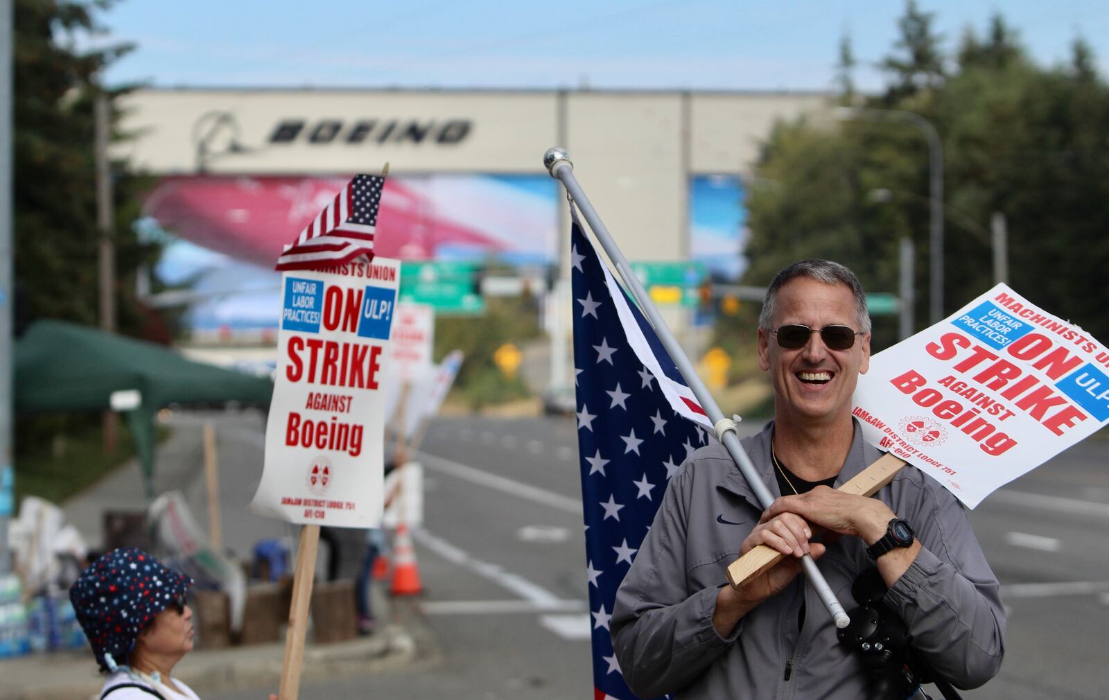 Union machinist Bill Studerus holds a picket sign and an American flag near Boeing's factory in Everett, Washington, Thursday, Sept. 19, 2024. (AP Photo/Manuel Valdes)