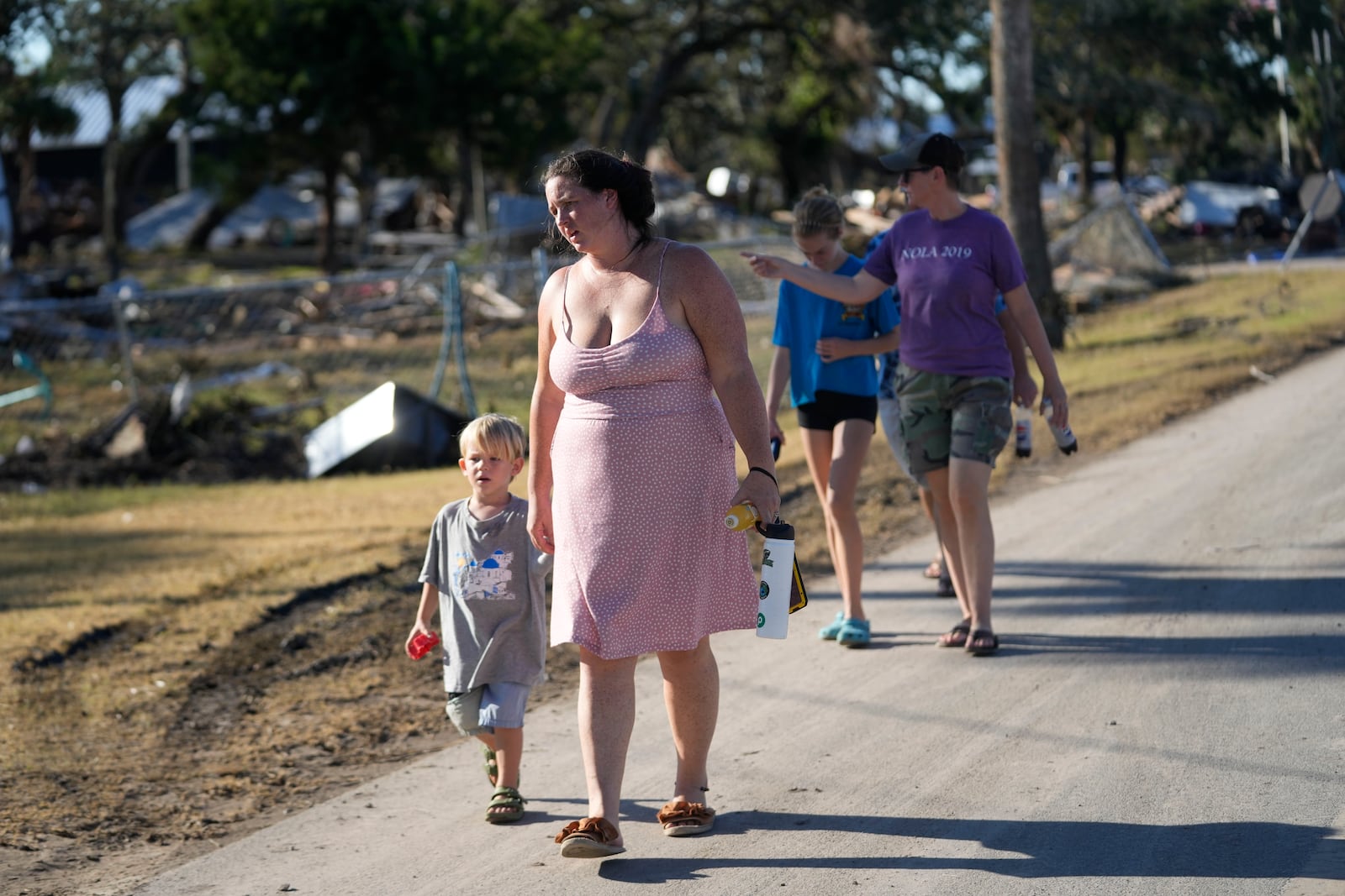 A group from St. Augustine, Fla. that arrived to help storm victims, who did not want to give their names, walk to the damaged First Baptist Church to pray in the aftermath of Hurricane Helene, in Horseshoe Beach, Fla., Sunday, Sept. 29, 2024. (AP Photo/Gerald Herbert)