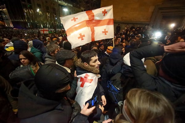 Protesters with a Georgian national flag pour into the streets following Kobakhidze's announcement, rallying outside the parliament building in Tbilisi, Georgia, on Thursday, Nov. 28, 2024. (AP Photo/Zurab Tsertsvadze)