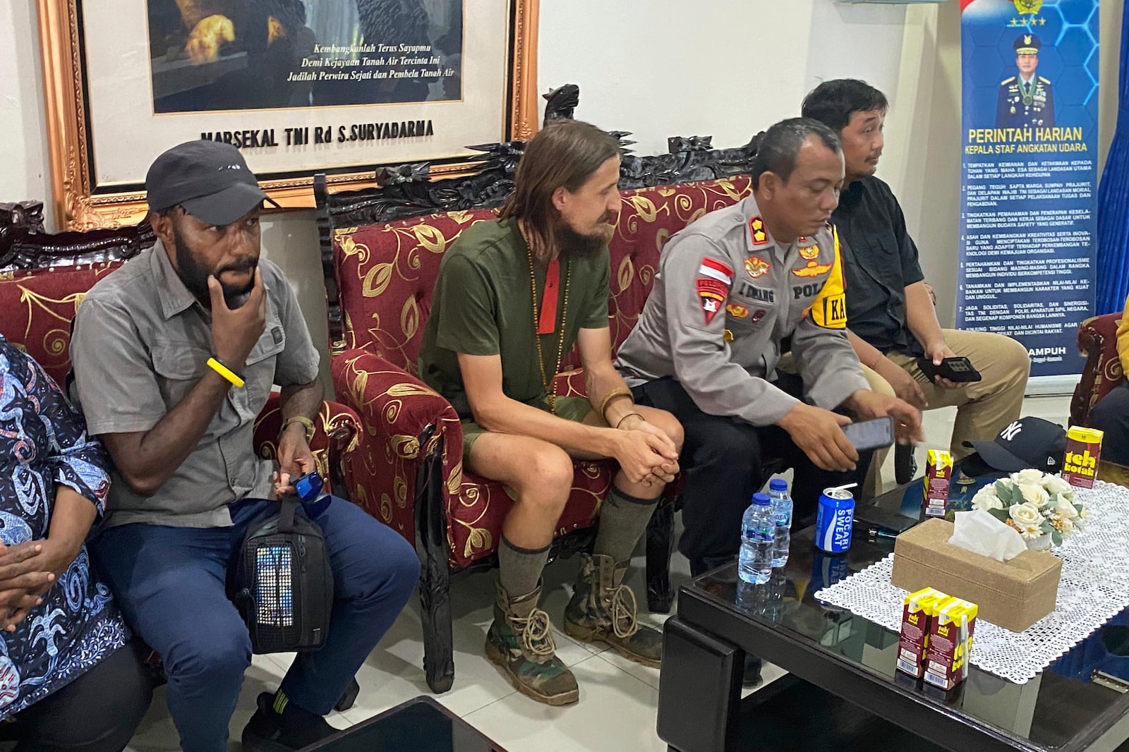 In this photo released by Cartenz Peace Task Force (Satgas Damai Cartenz) of the Indonesian security forces, New Zealand pilot Phillip Mehrtens, left, who was held hostage for more than a year in the restive Papua region, sits with police officers after his release, in Timika, Papua province, Saturday, Sept. 21, 2024. (Satgas Damai Cartenz via AP)