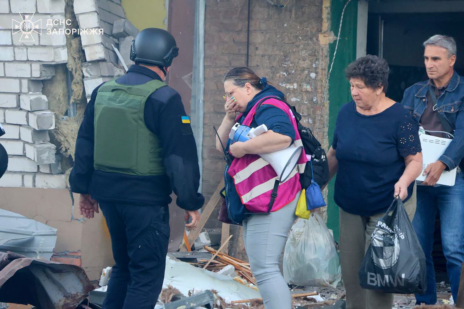 In this photo provided by the Ukrainian Emergency Service, residents carrying belongings leave their ruined home after Russia attacked the city with guided bombs overnight in Zaporizhzhia, Ukraine, Sunday, Sept. 29, 2024. (Ukrainian Emergency Service via AP)