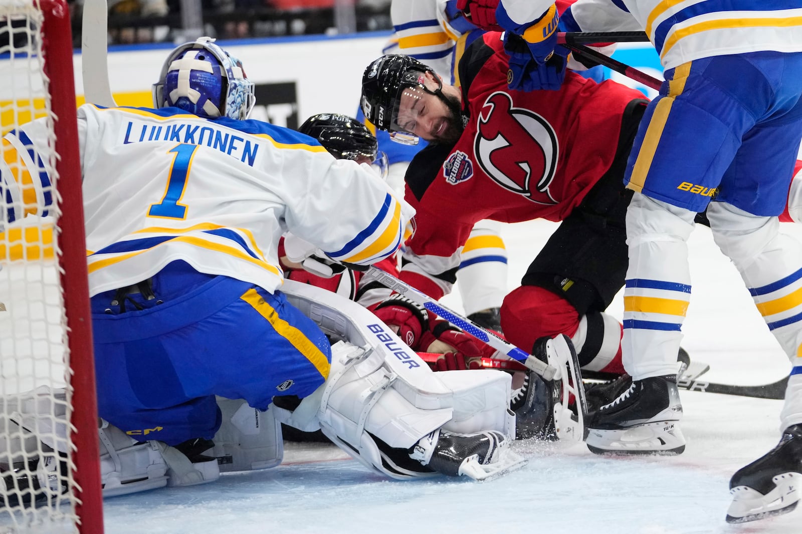 Buffalo Sabres' Ukko-Pekka Luukkonen, left, battles for the puck with New Jersey Devils' Tomas Tatar, second from right, during the NHL hockey game between Buffalo Sabres and New Jersey Devils, in Prague, Czech Republic, Friday, Oct. 4, 2024. (AP Photo/Petr David Josek)