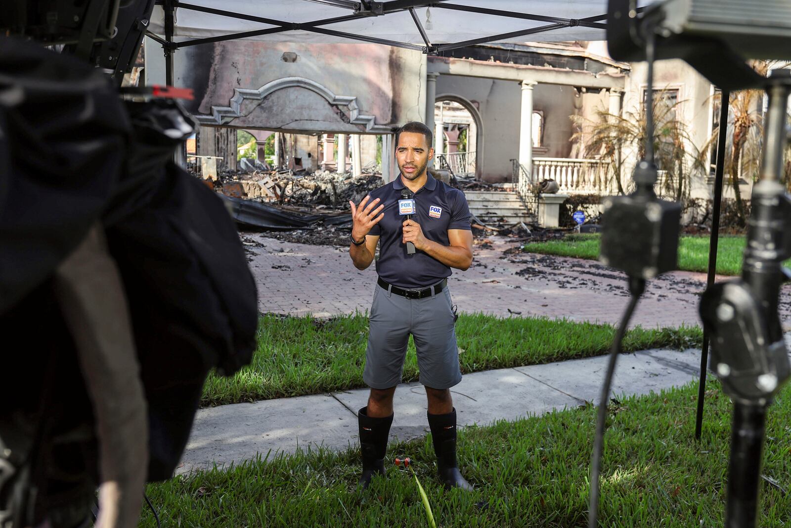 Fox Weather reporter Michael Estime broadcasts from in front of a home on Davis Island that burned during Hurricane Helene on Saturday, Sept. 28, 2024, in Tampa, Fla. (AP Photo/Mike Carlson)