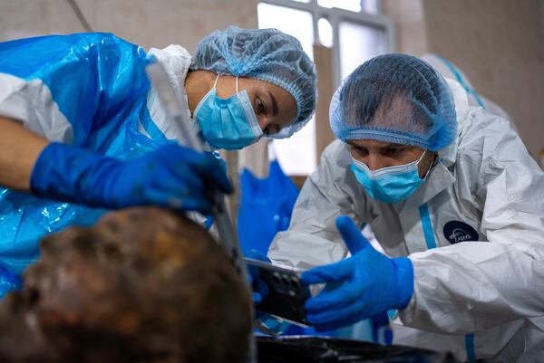 Forensic workers at a morgue in Kyiv, Ukraine, examine the body of a Ukrainian prisoner of war returned by Russia, June 24, 2024. (AP Photo/Alex Babenko)