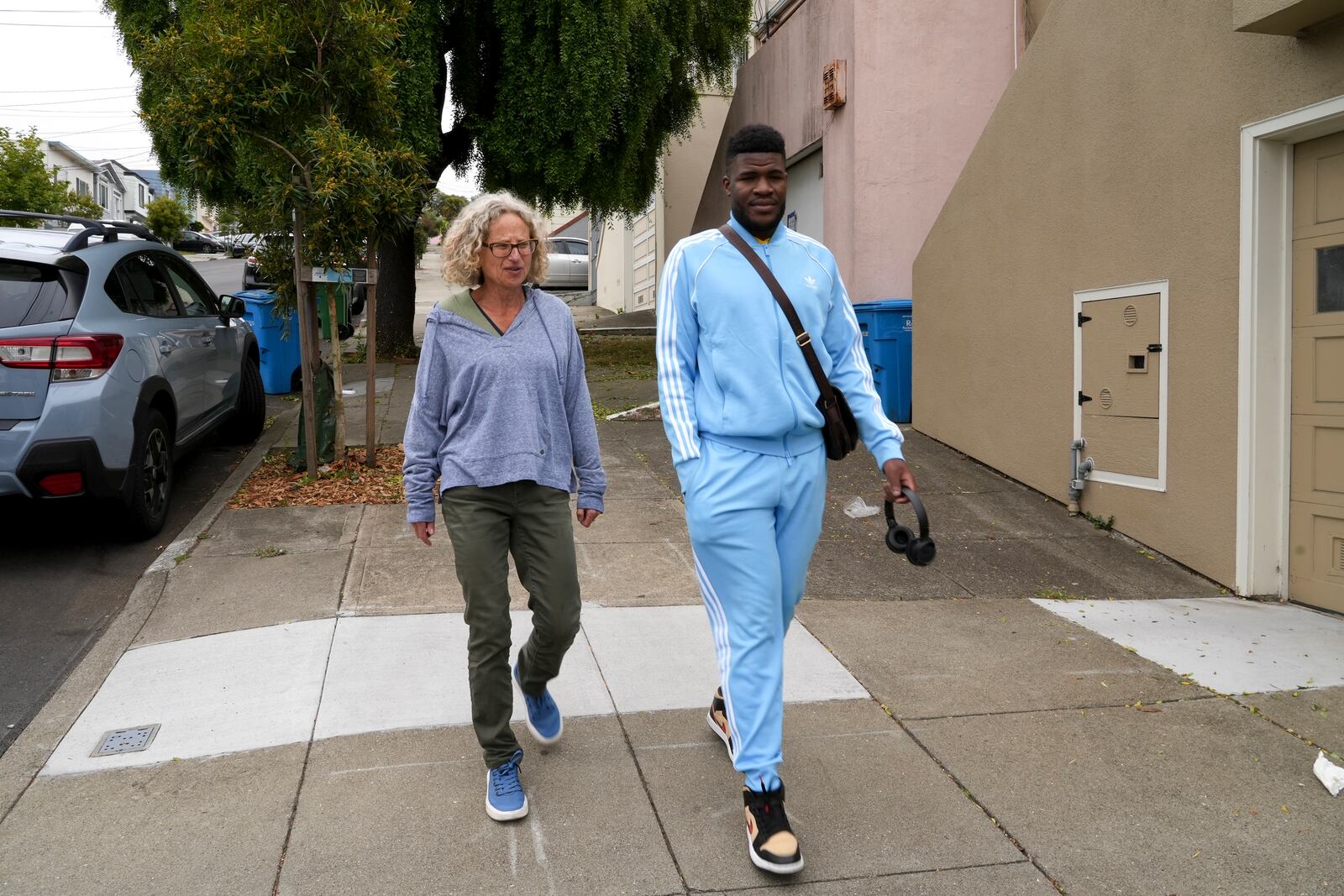 Cabrel Ngougou, a refugee from Cameroon, right, walks with his sponsor Anne Raeff in San Francisco Tuesday, Sept. 17, 2024. (AP Photo/Terry Chea)