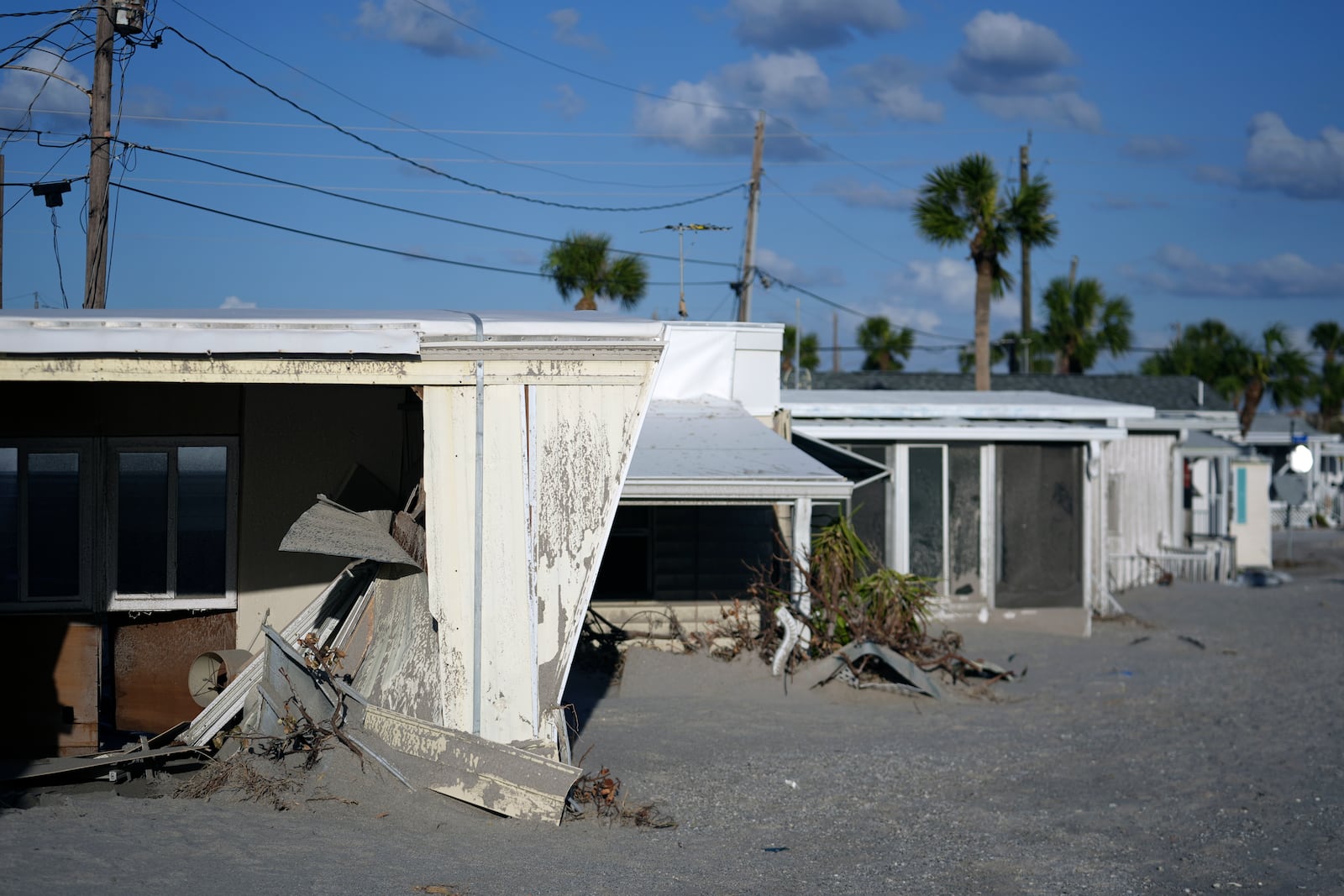 Trailers are engulfed by several feet of sand, at a mobile home community on Manasota Key, in Englewood, Fla., following the passage of Hurricane Milton, Sunday, Oct. 13, 2024. The property also lost its tiki hut and several beachfront units were severely damaged, but residents say they love their friendly beachfront community and want to preserve it. (AP Photo/Rebecca Blackwell)