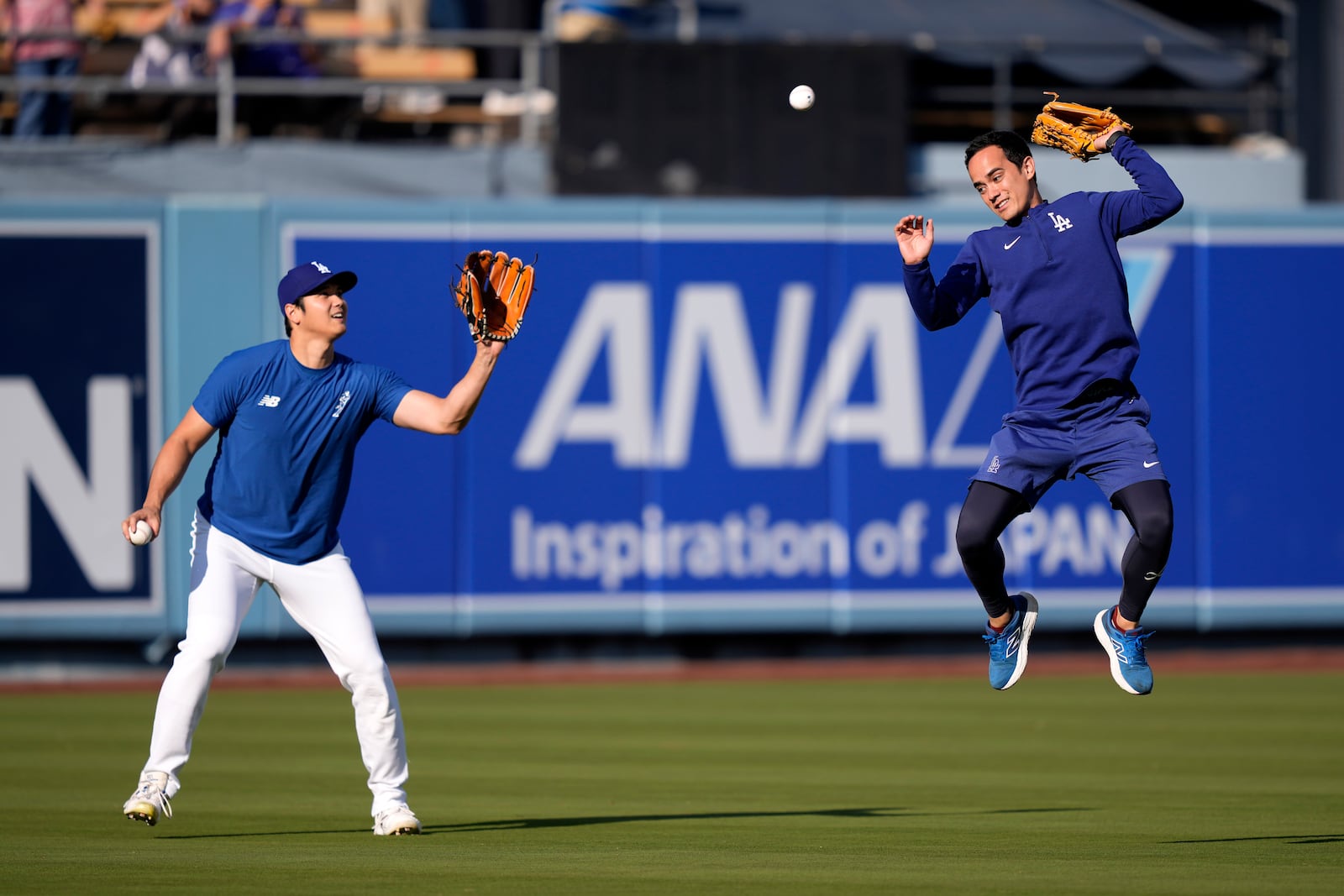 Los Angeles Dodgers interpreter Will Ireton, right, is unable to reach a batted ball while trying to protect Shohei Ohtani as Ohtani warms up prior to a baseball game against the San Diego Padres, Tuesday, Sept. 24, 2024, in Los Angeles. (AP Photo/Mark J. Terrill)