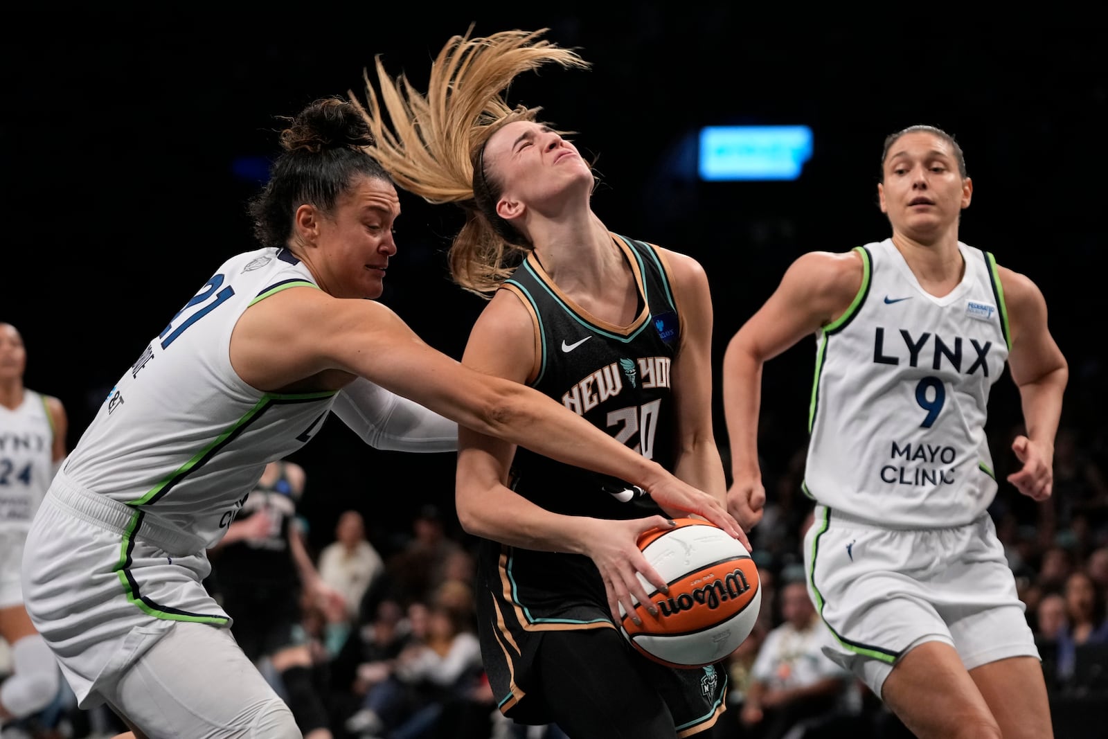 New York Liberty's Sabrina Ionescu, center, falls while dribbling against Minnesota Lynx's Kayla McBride, left, during the first half in Game 2 of a WNBA basketball final playoff series, Sunday, Oct. 13, 2024, in New York. (AP Photo/Pamela Smith)