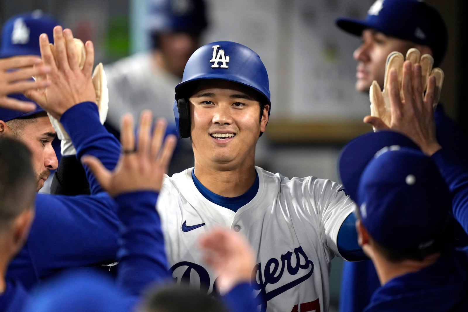 Los Angeles Dodgers' Shohei Ohtani is congratulated by teammates in the dugout after scoring on San Diego Padres shortstop Xander Bogaerts' error while trying to throw out Mookie Betts at first during the first inning of a baseball game, Tuesday, Sept. 24, 2024, in Los Angeles. (AP Photo/Mark J. Terrill)