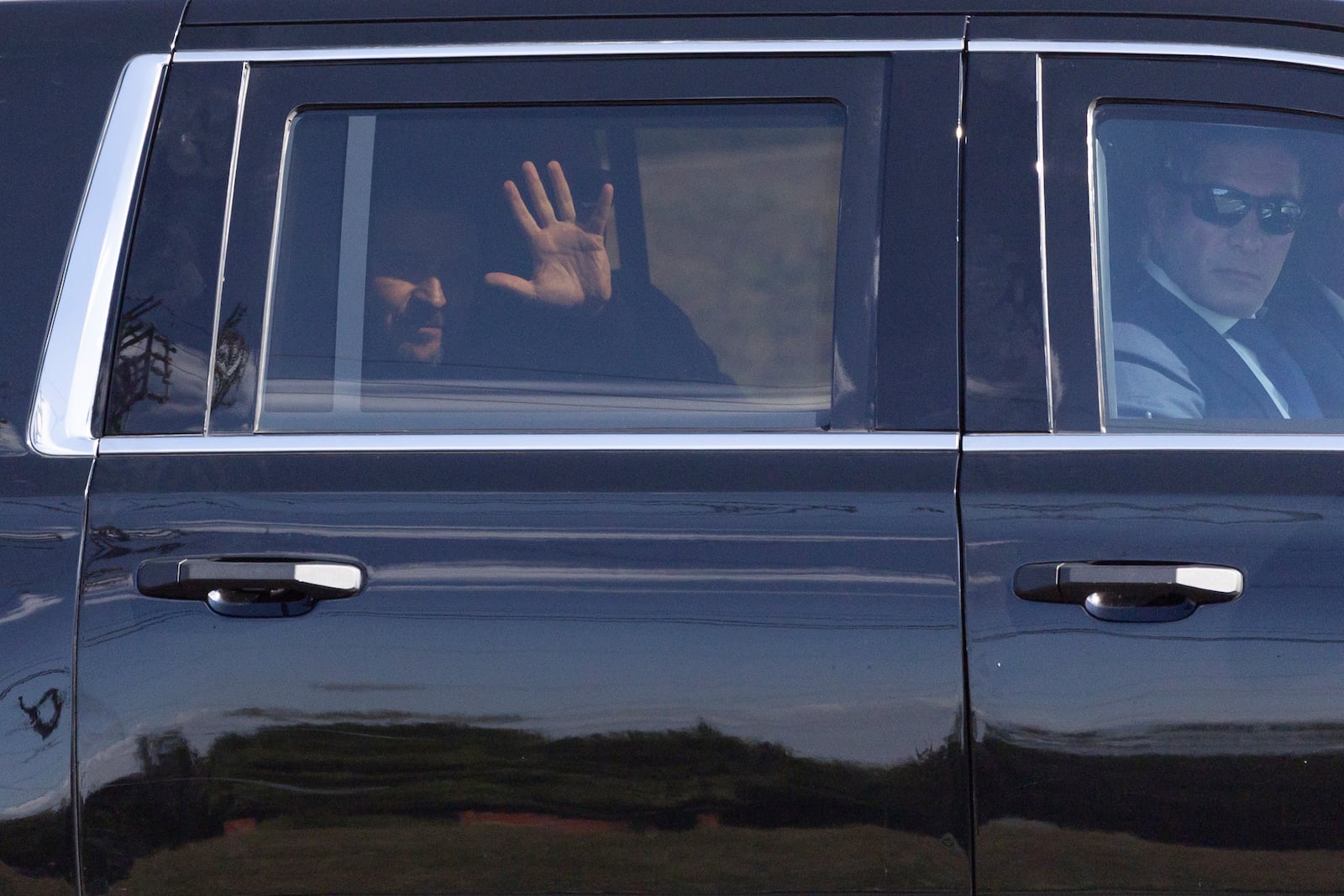 Ukrainian President Volodymyr Zelenskyy waves from the back seat of a U.S. Secret Service vehicle as his motorcade departs the Wilkes-Barre/Scranton International Airport in Pittston Township, Pa. en route to the Scranton Army Ammunition Plant in Scranton, Pa. on Sunday, Sept. 22, 2024. (Christopher Dolan/The Times-Tribune via AP)