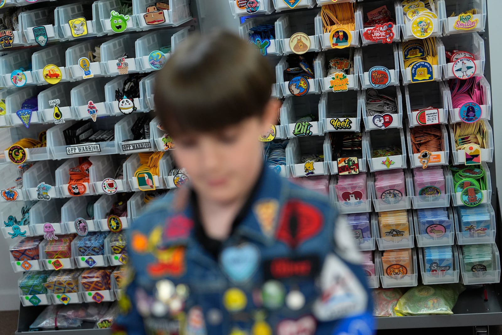 Oliver Burkhardt, 13, stands in front of trays of patches inside the offices of the Oliver Patch Project, Wednesday, Sept. 4, 2024, in Miami. (AP Photo/Rebecca Blackwell)