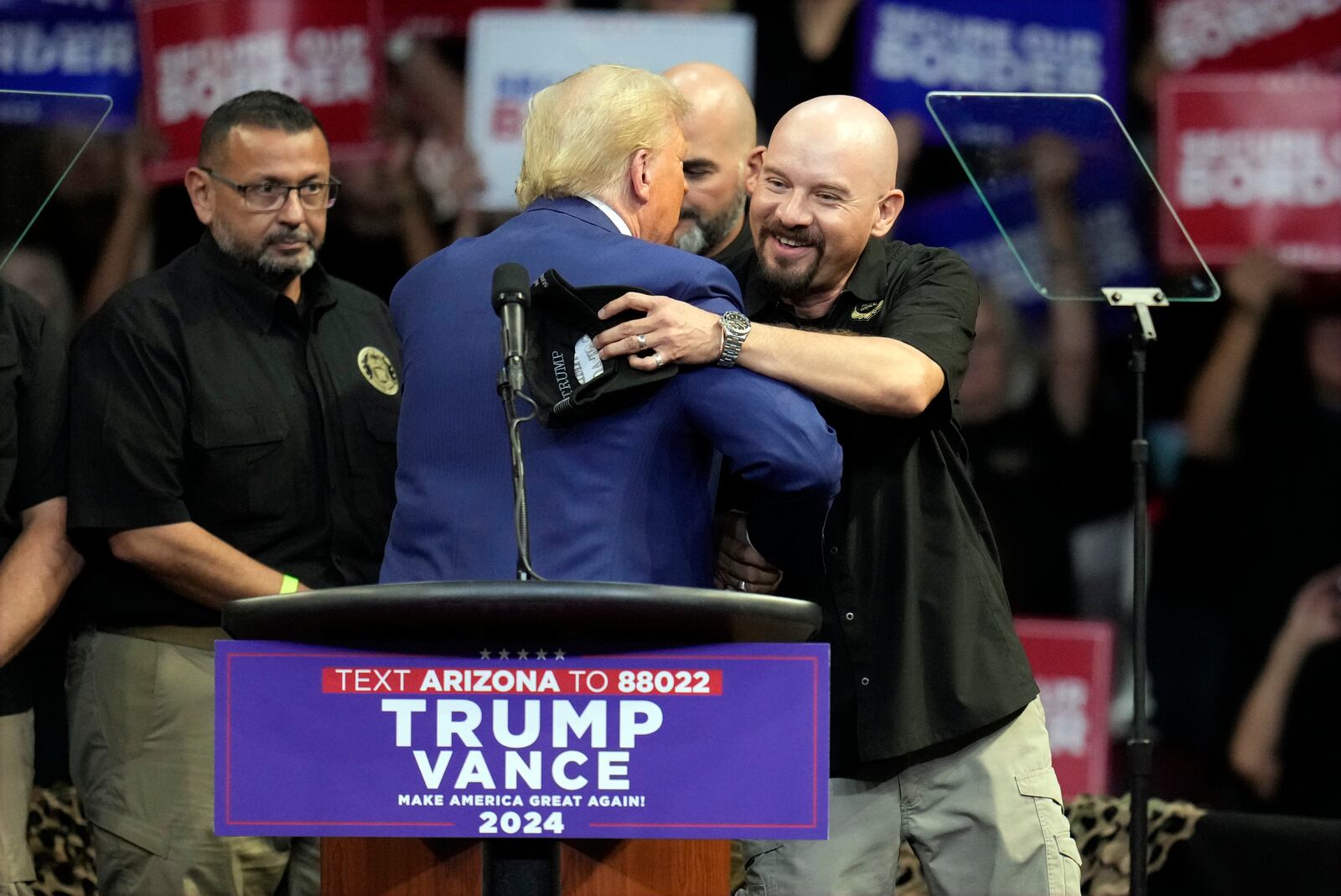 Art del Cueto, vice president of the National Border Patrol Council, embraces Republican presidential nominee former President Donald Trump at a campaign rally at the Findlay Toyota Arena Sunday, Oct. 13, 2024, in Prescott Valley, Ariz. (AP Photo/Ross D. Franklin)