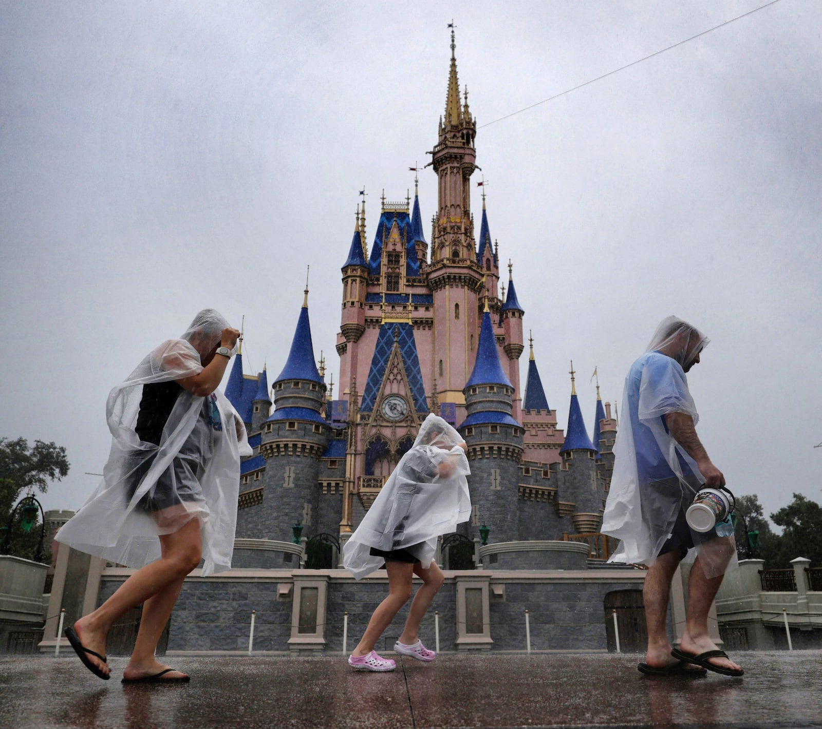 Guests weather early bands of rain from Hurricane Milton at the Magic Kingdom at Walt Disney World in Bay Lake, Fla., Wednesday, Oct. 9, 2024. All four of Disney's Florida theme parks closed early Wednesday due to the forecast track of the storm. (Joe Burbank/Orlando Sentinel via AP)