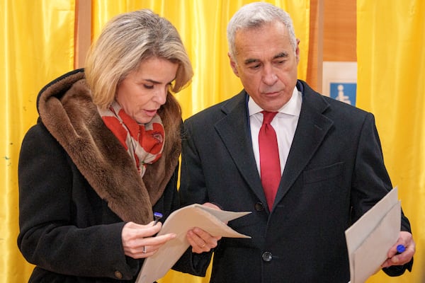 Calin Georgescu, an independent candidate for president who came first after the first round of presidential election, and his wife Cristela talk before casting their vote in the country's parliamentary election in Mogosoaia, Romania, Sunday, Dec. 1, 2024. (AP Photo/Andreea Alexandru)