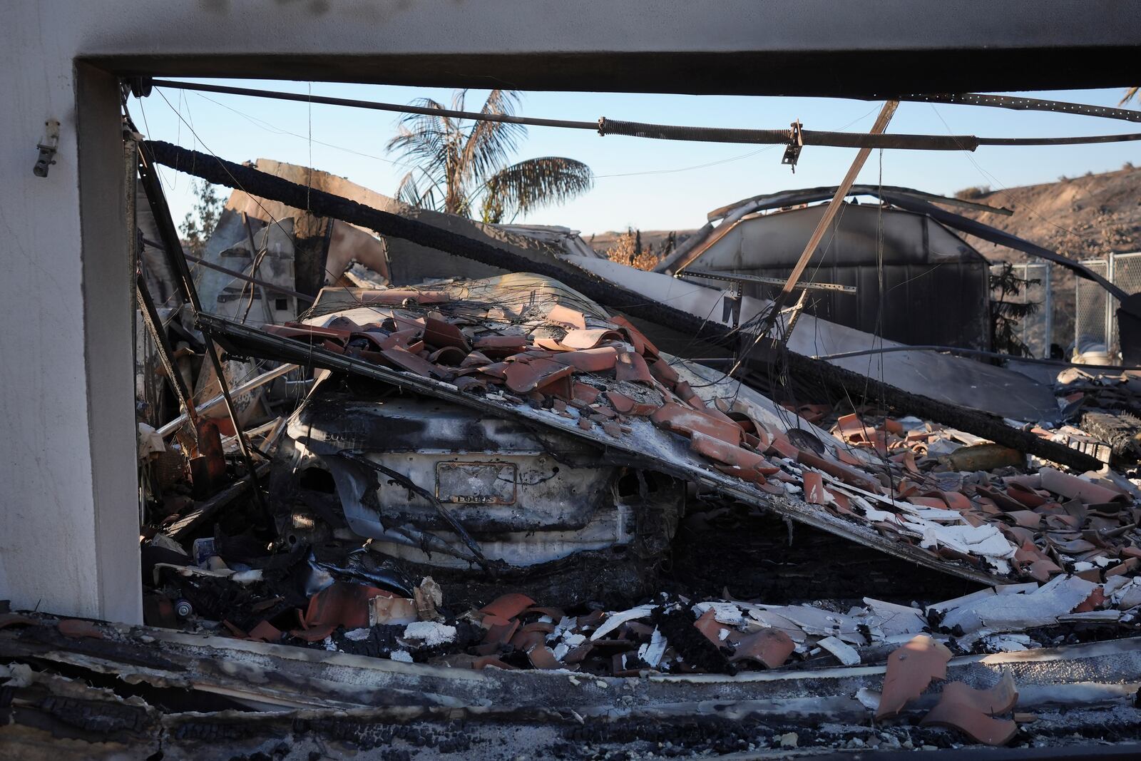 The remains of a car sit under debris at the site of a home destroyed by the Mountain Fire in Camarillo, Calif., Friday, Nov. 8, 2024. (AP Photo/Jae C. Hong)