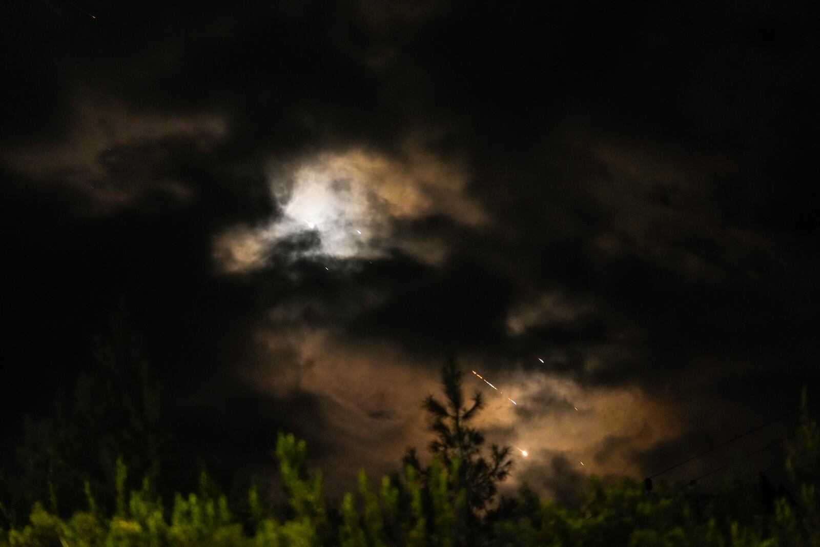 Projectiles fly through the sky in central Israel as a siren sounds a warning of incoming missiles fired from Iran towards Israel, Tuesday, Oct. 1, 2024. (AP Photo/Ohad Zwigenberg)