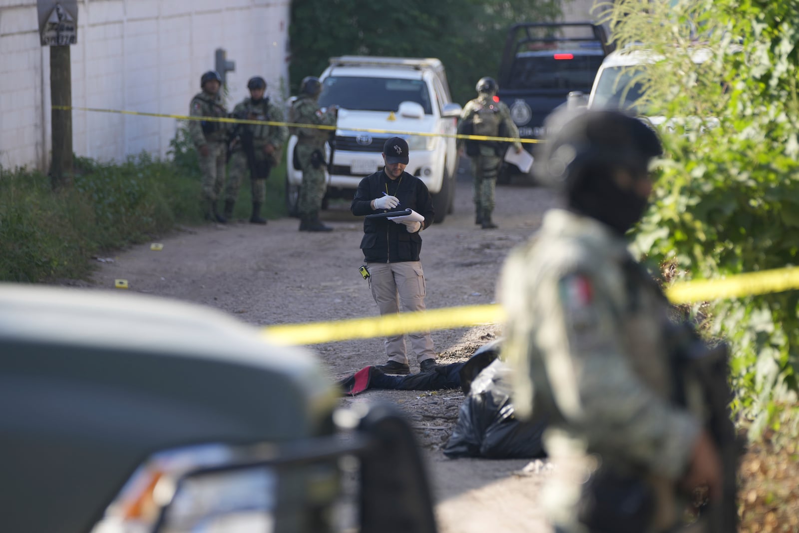 Forensic investigators work at the site of a body lying in the street in La Costerita, Culiacan, Sinaloa state, Mexico, Thursday, Sept. 19, 2024. (AP Photo/Eduardo Verdugo)