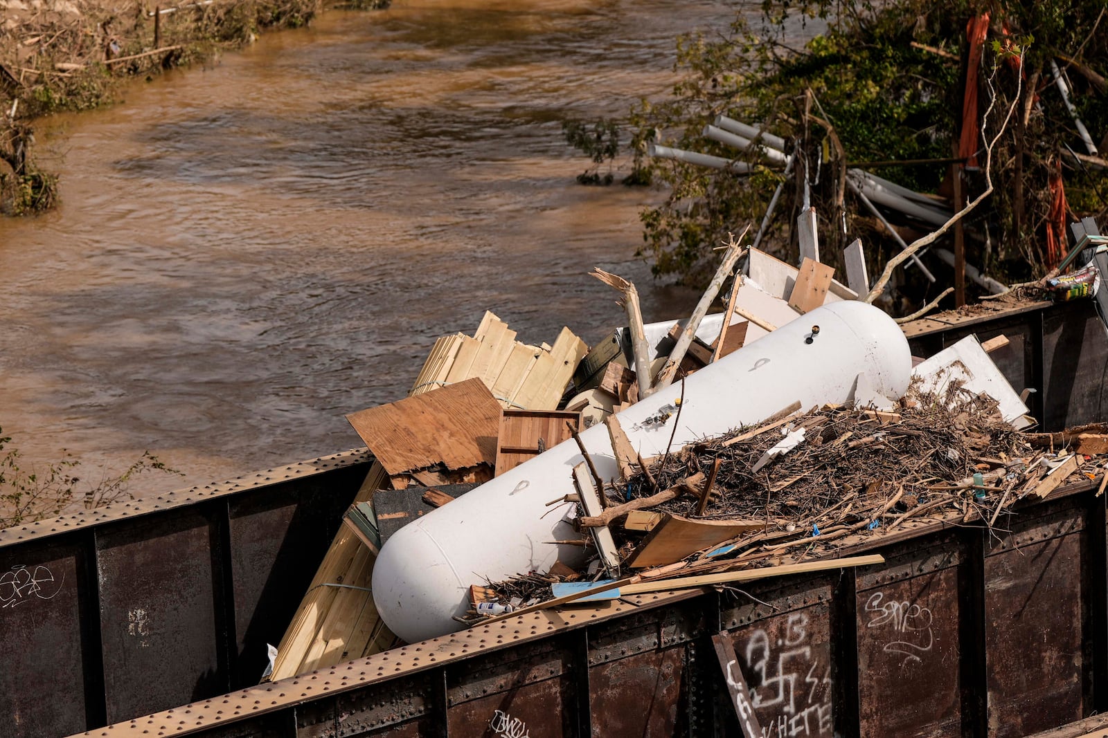 A gas natural gas tank lies with other debris on a train bridge in the aftermath of Hurricane Helene, Monday, Sept. 30, 2024, in Ashville, N.C. (AP Photo/Mike Stewart)