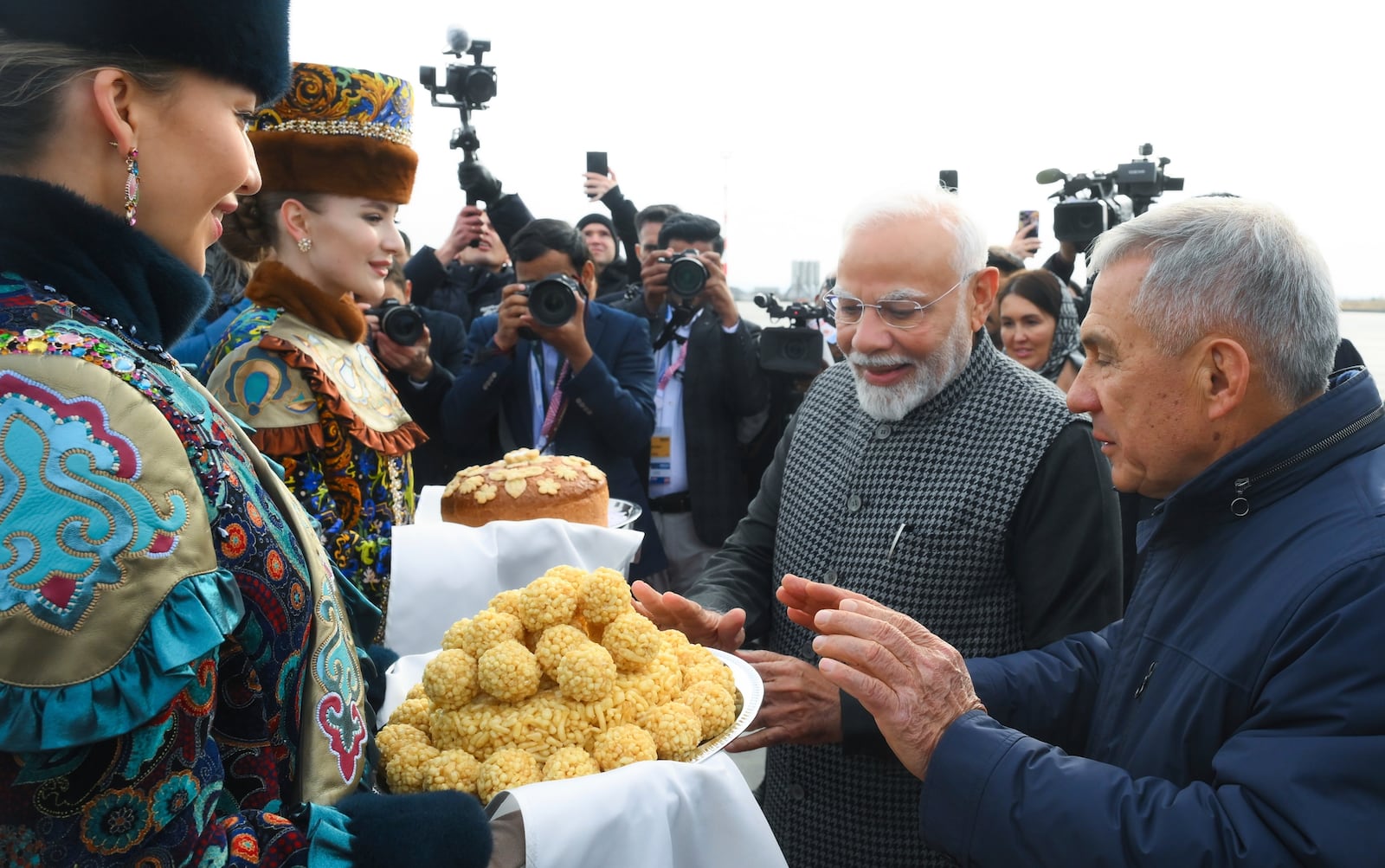 Indian Prime Minister Narendra Modi, second right, tries Tatar traditional sweet Chak-chak upon his arrival at Kazan International Airport for the BRICS Summit in Kazan, Russia, Tuesday, Oct. 22, 2024. (Ilya Pitalev/Photo host brics-russia2024.ru via AP)