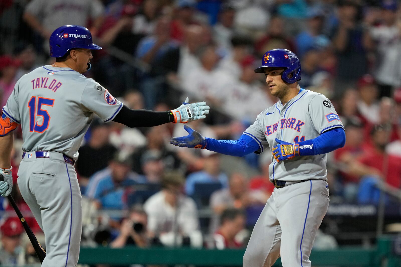 New York Mets' Jose Iglesias, right, and Tyrone Taylor celebrate after Iglesias scored on a sacrifice fly by Starling Marte during the eighth inning of Game 1 of a baseball NL Division Series, Saturday, Oct. 5, 2024, in Philadelphia. (AP Photo/Matt Slocum)