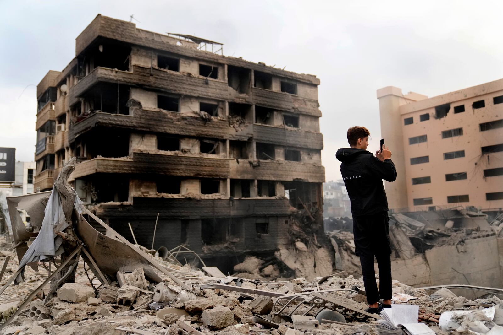 A man takes pictures by his mobile phone of destroyed buildings hit by Israeli airstrikes in Dahiyeh, Beirut, Lebanon, Monday, Oct. 7, 2024. (AP Photo/Hussein Malla)