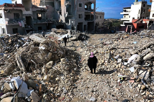 Residents walk past destroyed buildings as they return to Qana village, southern Lebanon, Thursday, Nov. 28, 2024 following a ceasefire between Israel and Hezbollah that went into effect on Wednesday.(AP Photo/Hussein Malla)