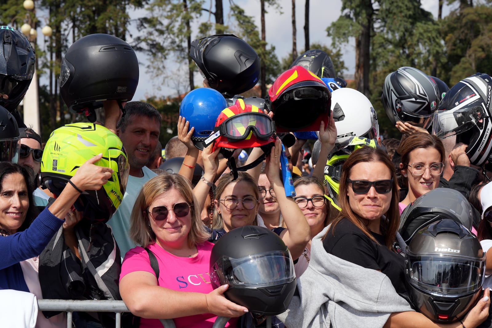 Two red firefighter helmets are held up among motorcyclist helmets being blessed during the IX Pilgrimage of the Blessing of Helmets that draws tens of thousands at the Roman Catholic holy shrine of Fatima, in Fatima, Portugal, Sunday, Sept. 22, 2024. (AP Photo/Ana Brigida)